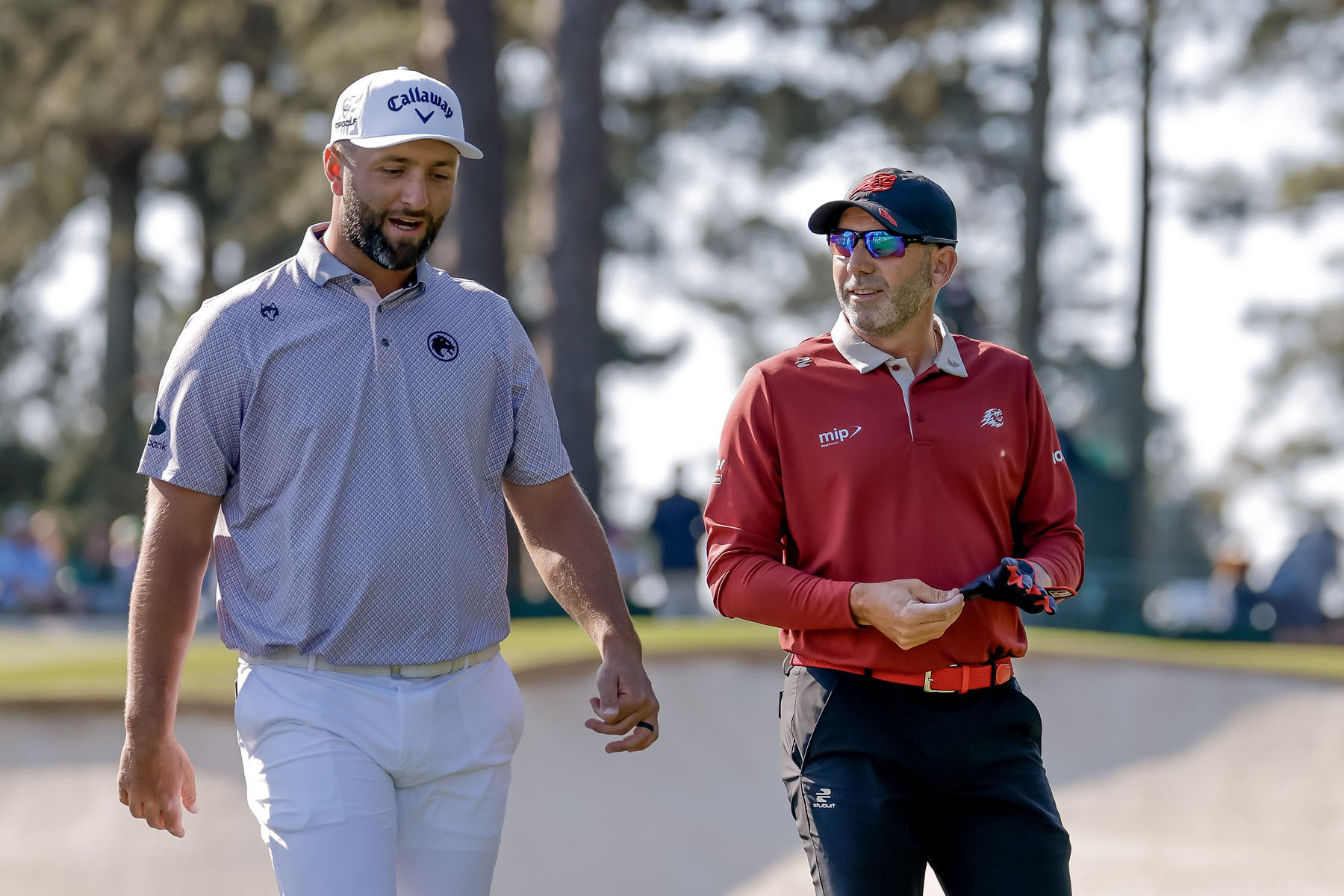 Jon Rahm (vlevo) a Sergio García odcházejí z odpaliště třetí jamky během finálového kola The Masters Tournament 2026