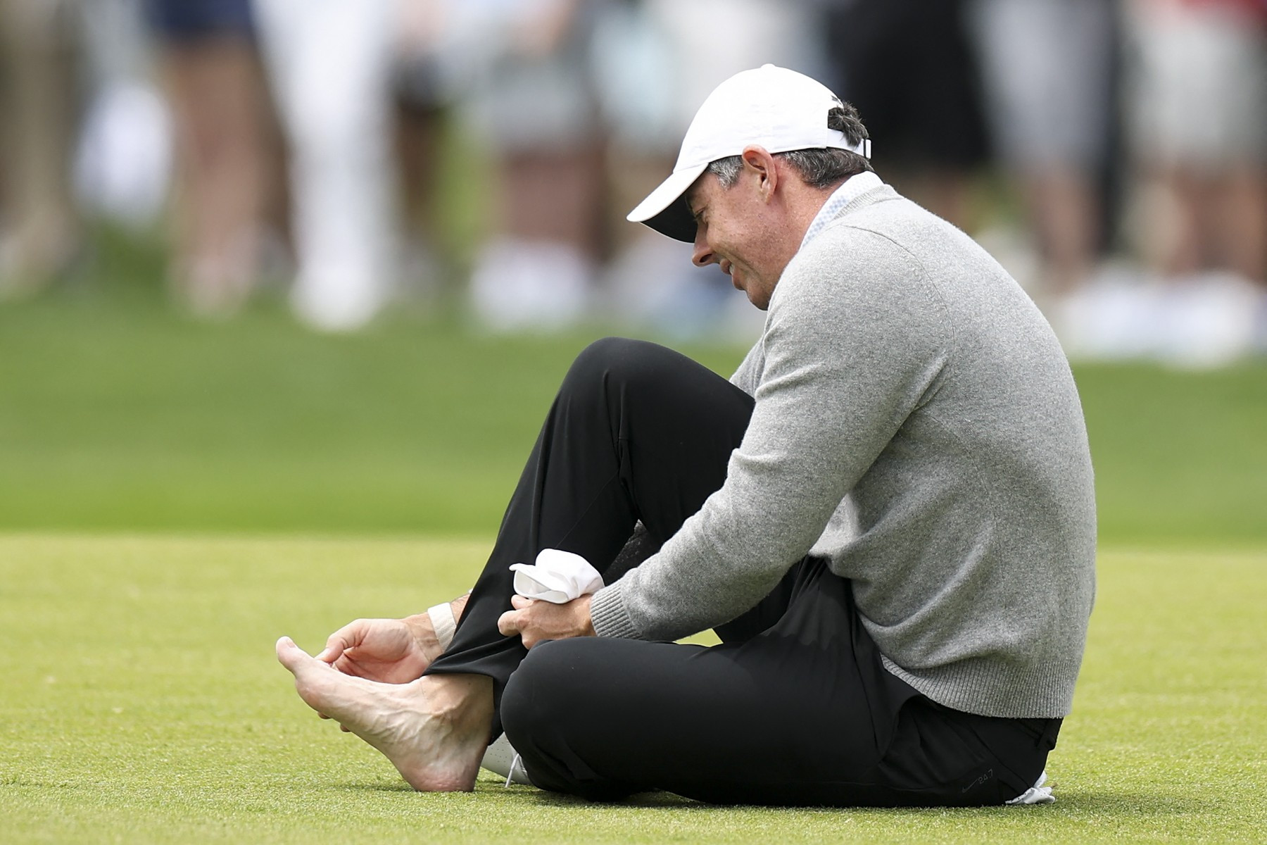 Rory McIlroy si ošetřuje nohu na 18. jamce během cvičného kola před turnajem PGA Championship v golfovém klubu Aronimink