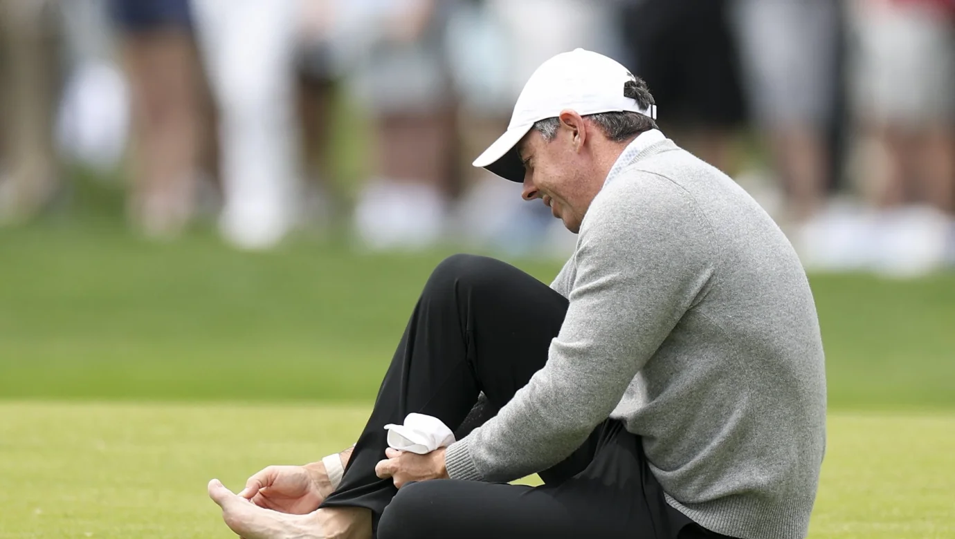 Rory McIlroy si ošetřuje nohu na 18. jamce během cvičného kola před turnajem PGA Championship v golfovém klubu Aronimink